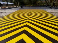 Demarcación antideslizante amarilla y negra sobre piso de concreto a la intemperie